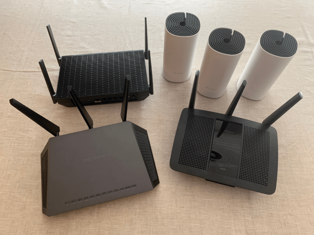 Linksys MR9600, Tp-Link Deco S4, Netgear R7000 and Linksys EA7300 side by side